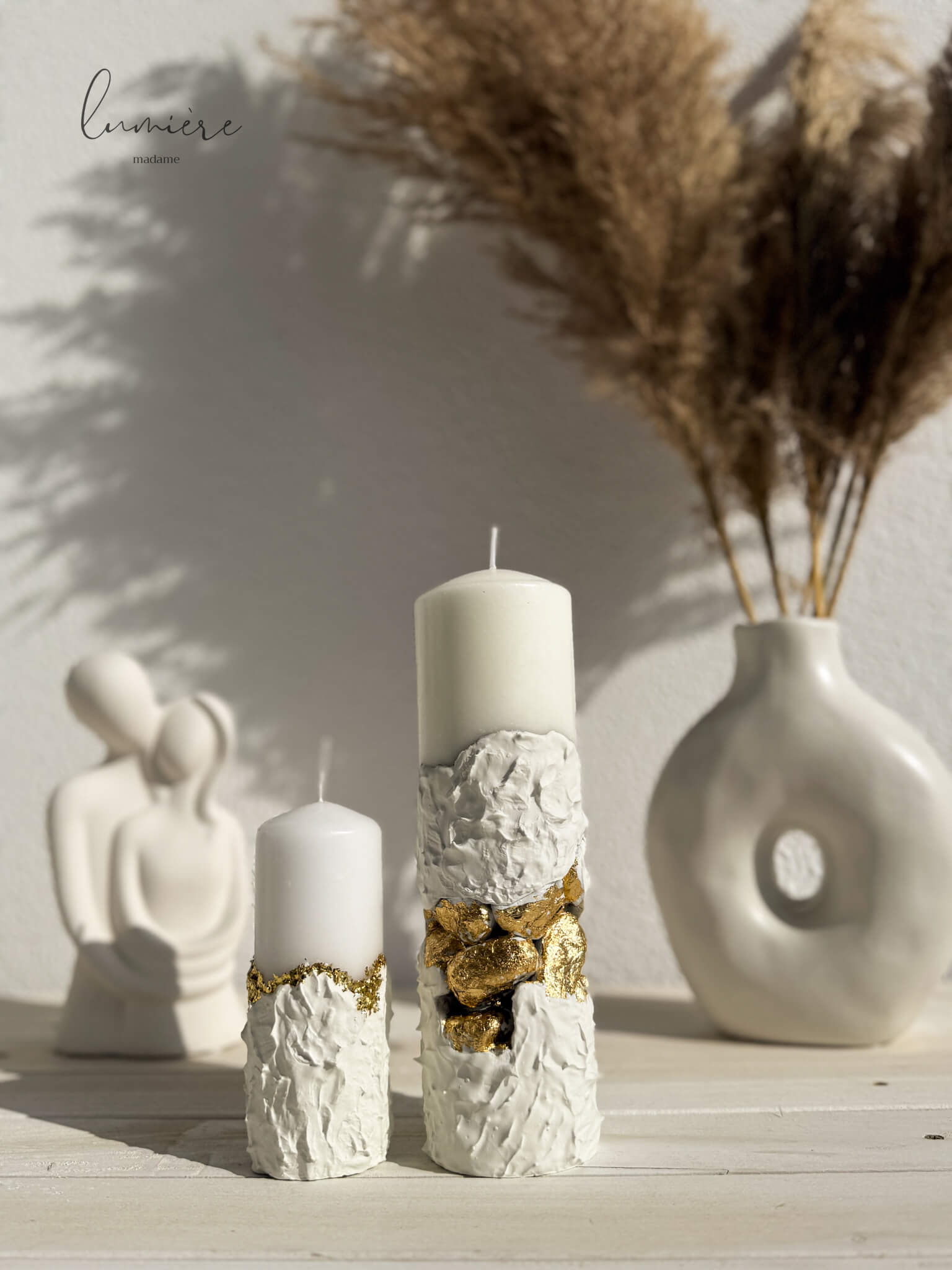 Lumânare albă sculpturală cu pietre aurii decorative, realizată manual din ciment cu design premium.