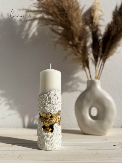 Lumânare albă sculpturală cu pietre aurii decorative, realizată manual din ciment cu design premium.