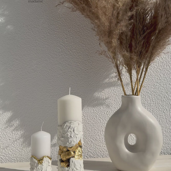 Lumânare albă sculpturală cu pietre aurii decorative, realizată manual din ciment cu design premium.